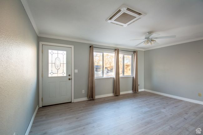 Entryway featuring light colored LVP flooring, crown molding, ceiling fan, and a healthy amount of sunlight | Image 4