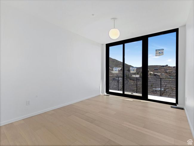 Unfurnished room featuring light wood-style floors, visible vents, baseboards, and a wall of windows | Image 31