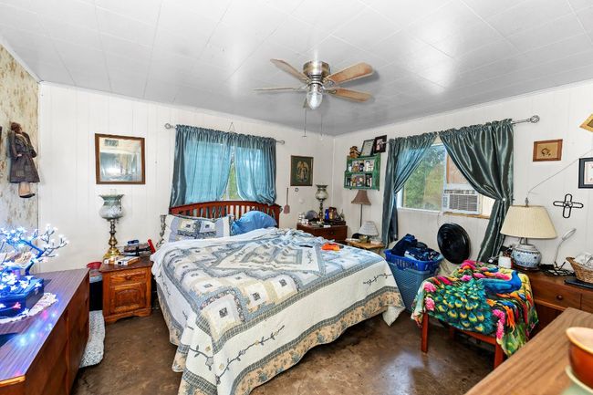 Bedroom with finished concrete floors, ceiling fan, and cooling unit | Image 12