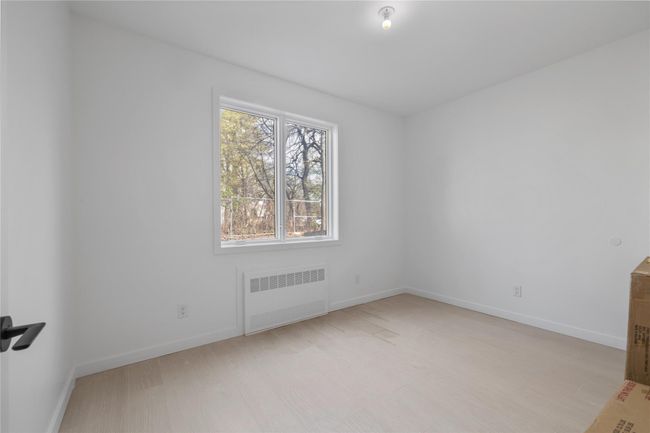Unfurnished room featuring radiator heating unit, baseboards, and light wood-style flooring | Image 43