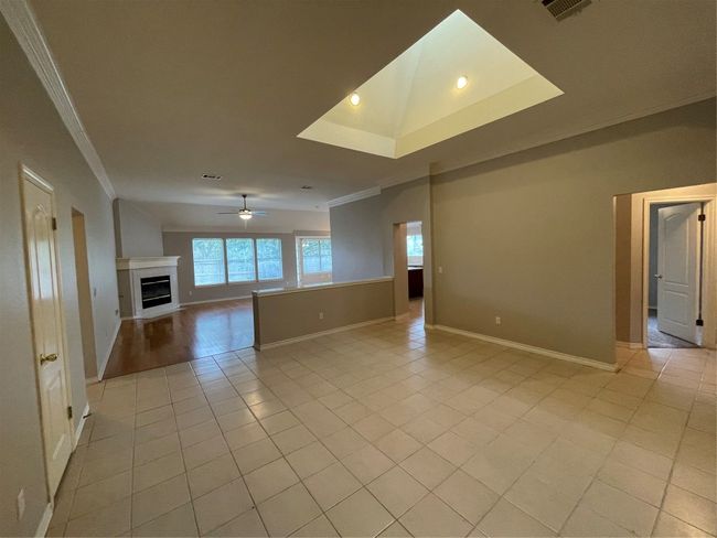 Unfurnished living room featuring ornamental molding, light tile patterned floors, ceiling fan, a tile fireplace, and recessed lighting | Image 5