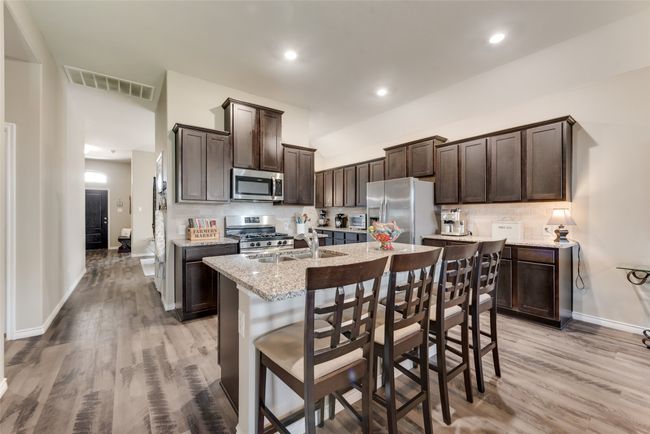 Kitchen with stainless steel appliances, dark brown cabinets, backsplash, light wood-style flooring, and recessed lighting | Image 13