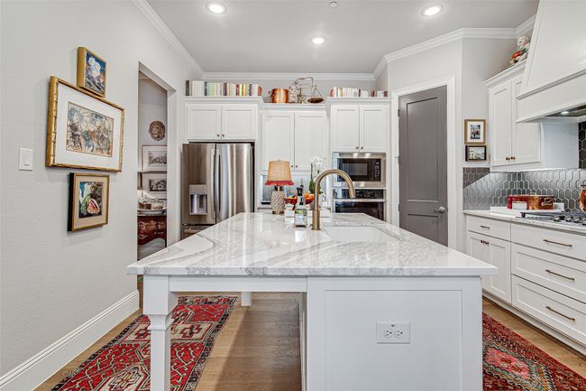 Kitchen featuring white cabinets, a sink, stainless steel appliances, a center island with sink, and backsplash | Image 12