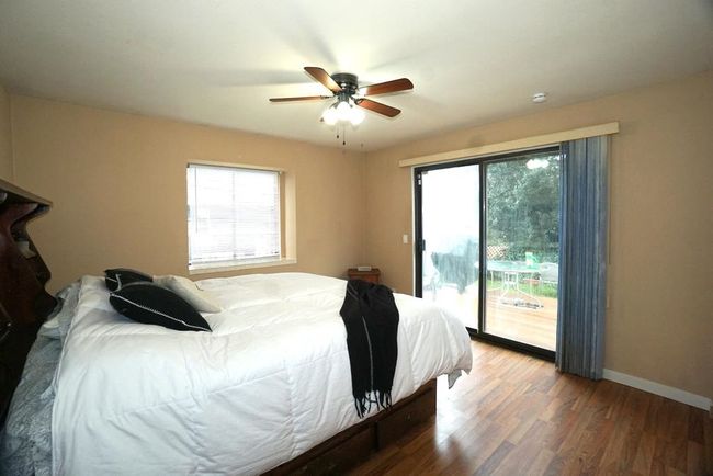 Bedroom featuring access to exterior, multiple windows, wood finished floors, and a ceiling fan | Image 12