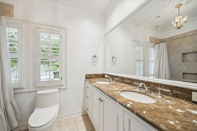 Upstairs full bath features dual sinks, Emperador marble counters, sweet chandelier and tub/shower combo. | Image 26