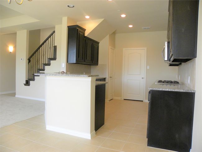 Kitchen featuring light colored carpet, gas stovetop, light stone countertops, recessed lighting, and backsplash | Image 15