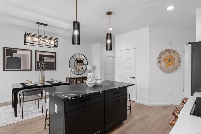 Kitchen featuring decorative light fixtures, a kitchen island, a kitchen breakfast bar, and light hardwood / wood-style flooring | Image 10