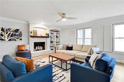 Living room with ornamental molding, a wealth of natural light, LV flooring/ plantation shutters, and a fireplace | Image 2