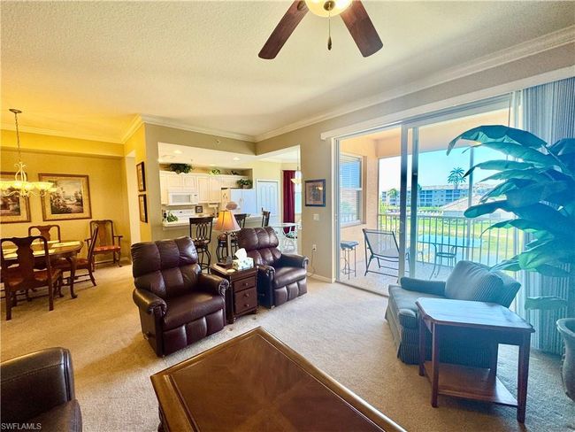 Living room with baseboards, ornamental molding, a textured ceiling, light carpet, and ceiling fan with notable chandelier | Image 5
