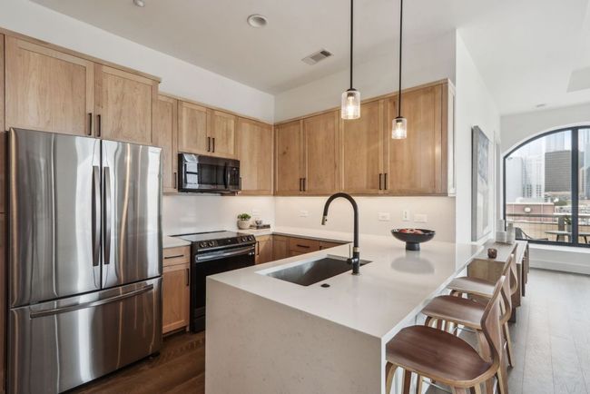 Kitchen featuring visible vents, range with electric stovetop, a sink, freestanding refrigerator, and a peninsula | Image 7