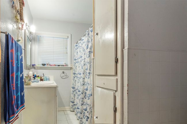 Bathroom with tile patterned flooring, tile walls, curtained shower, and vanity | Image 15