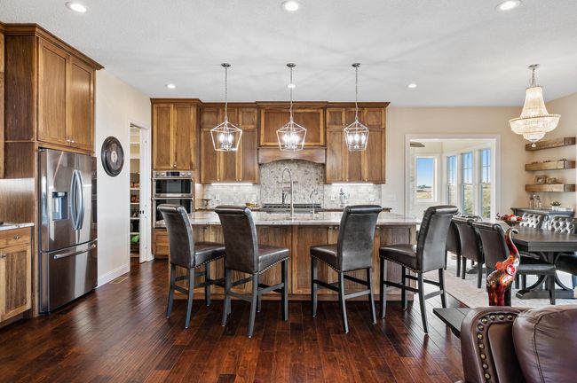 This chef's paradise features abundant cabinetry, a ZLINE 6-burner gas range with pot filler, a double wall oven, walk-in pantry, and an apron-front sink on a spacious island with breakfast bar seating—perfect for entertaining! | Image 6