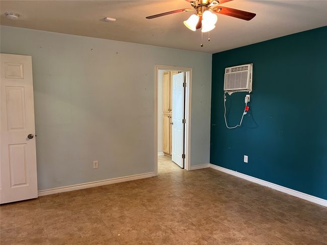 Unfurnished room featuring a smoke detector, ceiling fan, a wall mounted air conditioner, and baseboards | Image 17