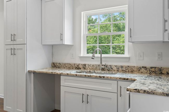 Kitchen featuring a sink, white cabinetry, and light stone counters | Image 9