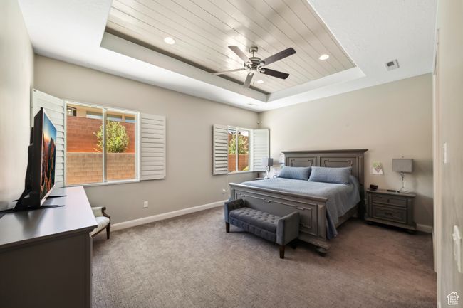 Carpeted bedroom featuring ceiling fan, a raised ceiling, baseboards, visible vents, and recessed lighting | Image 15