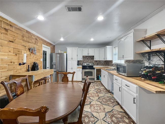 Kitchen featuring appliances with stainless steel finishes, wood counters, crown molding, tasteful backsplash, and white cabinetry | Image 15