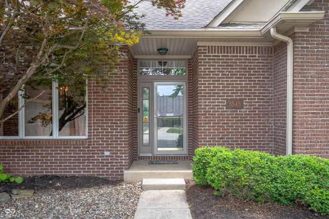 view of exterior entry featuring brick siding and a shingled roof | Image 4