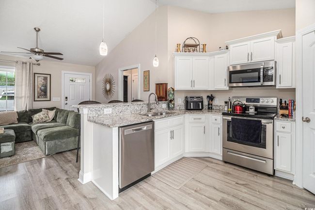 Kitchen with stainless steel appliances, a sink, open floor plan, a peninsula, and ceiling fan | Image 8