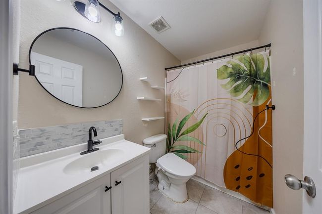 The bathroom downstairs features a beautiful round mirror, adding a stylish and elegant touch to the space. | Image 18