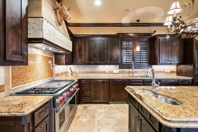 Kitchen featuring range with two ovens, a sink, knotty alder cabinetry and ornamental molding | Image 13