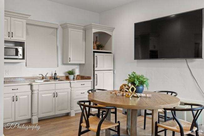 Kitchen featuring stainless steel microwave, a sink, light wood-type flooring, white cabinetry, and open shelves | Image 70