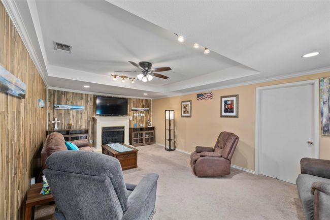 Den with fireplace and tray ceilings. Behind the door is a large storage area that runs the length of the room. It is deep and wide, great for Christmas decorations or needed space for large items or many items. | Image 19