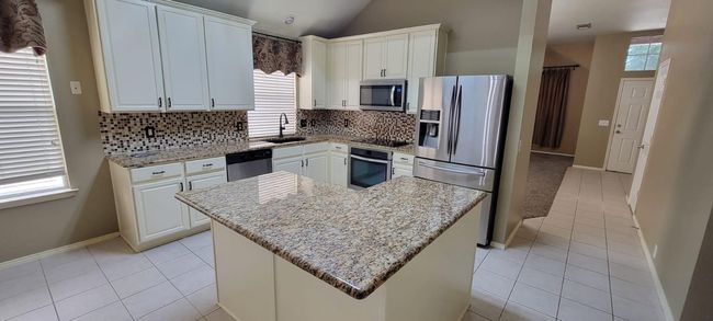 Kitchen featuring tasteful backsplash, plenty of natural light, appliances with stainless steel finishes, and lofted ceiling | Image 6