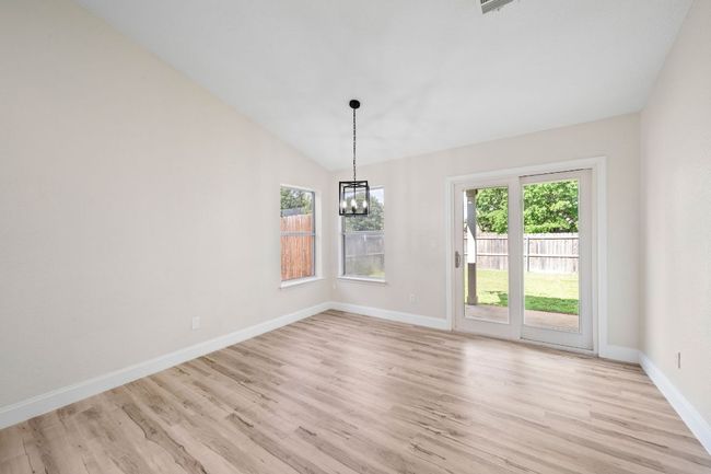 Unfurnished dining area with a chandelier, light wood finished floors, and vaulted ceiling | Image 9