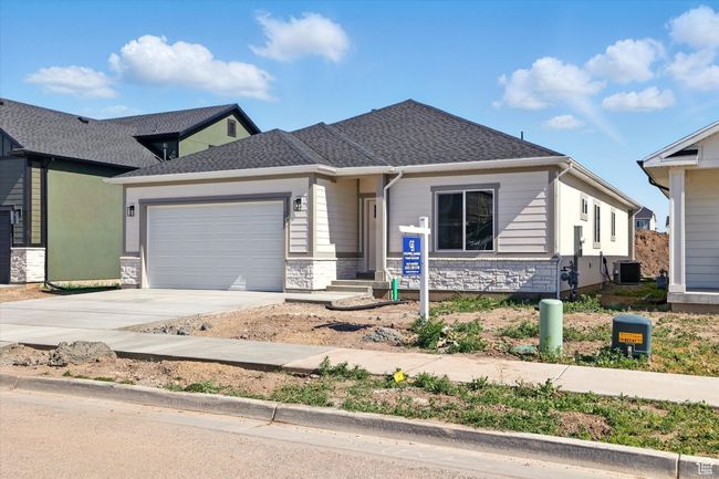 View of front of property featuring central AC unit, a garage, driveway, and stone siding | Image 32