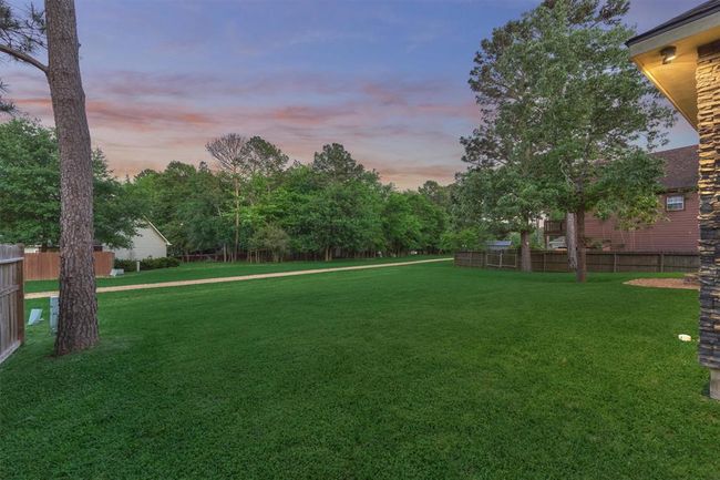 The spacious backyard offers the flexibility to be fenced in for added privacy or left open to fully enjoy the natural surroundings. With plenty of room for outdoor games, entertaining, or even adding a pool, this space is can be customized to suit your lifestyle. | Image 41