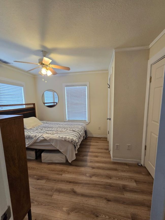 Bedroom with dark wood-style flooring, a textured ceiling, ornamental molding, and ceiling fan | Image 21