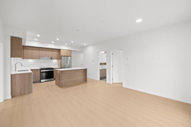 Kitchen with freestanding refrigerator, modern cabinets, range with electric cooktop, a kitchen island, and light countertops | Image 8