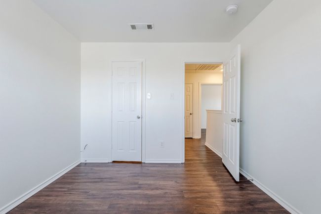 Unfurnished bedroom with dark wood-type flooring and baseboards | Image 26