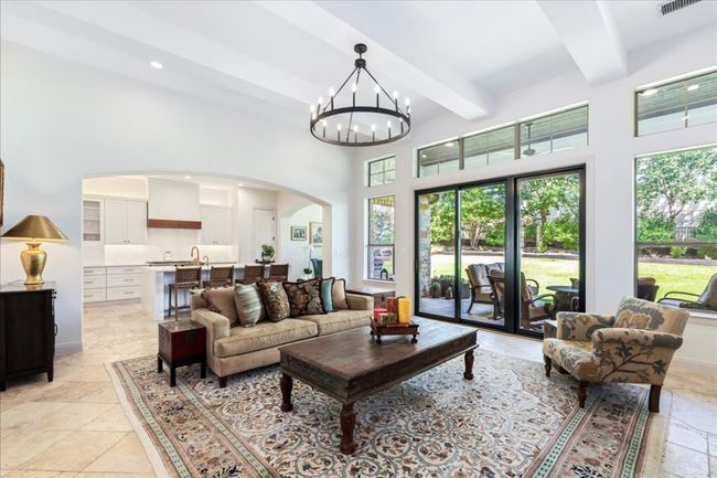 Living room featuring arched walkways, beamed ceiling, a high ceiling, a chandelier, and recessed lighting | Image 5