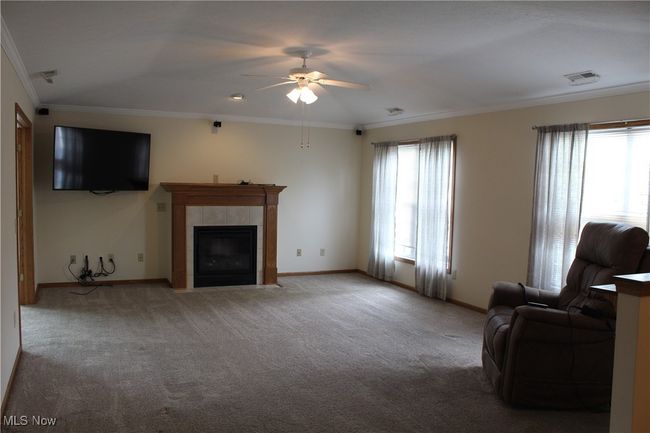 Living area featuring ornamental molding, a ceiling fan, light carpet, and a fireplace | Image 5