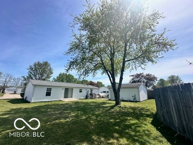 rear view of house featuring an outdoor structure, a lawn, a storage shed, and fence | Image 18