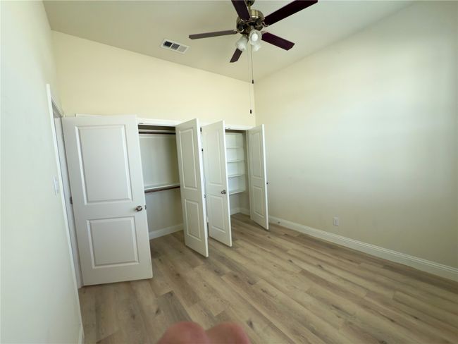 Unfurnished bedroom with light wood-style flooring, baseboards, two closets, and ceiling fan | Image 18