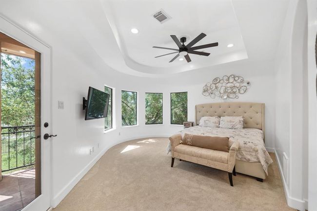 The third bedroom has a tray ceiling with recessed lighting and ceiling fan with light fixture, pre-wiring for a wall mounted flat screen TV, a curved wall of fixed glass windows, private access to the second floor covered patio & new carpet. This bedroom includes access to a shared full bath with the fourth bedroom. | Image 33