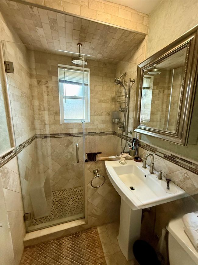 Bathroom featuring tile walls, a sink, and a shower stall | Image 12