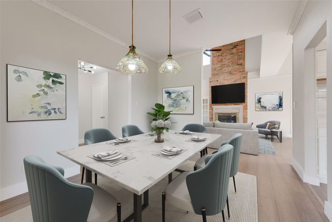 Dining space with light wood-style floors, a towering ceiling, a fireplace, and ornamental molding | Image 7