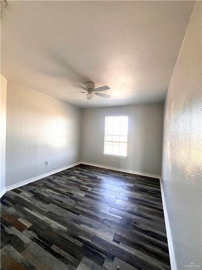 Bedroom featuring wood finished floors, a ceiling fan, baseboards, a textured ceiling, and a textured wall | Image 7