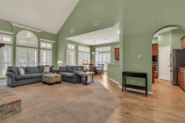 Living room featuring arched walkways, light wood-type flooring, visible vents, and high vaulted ceiling | Image 18