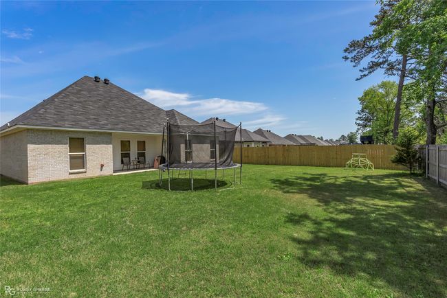 View of yard featuring a trampoline, a fenced backyard, and a patio area | Image 28