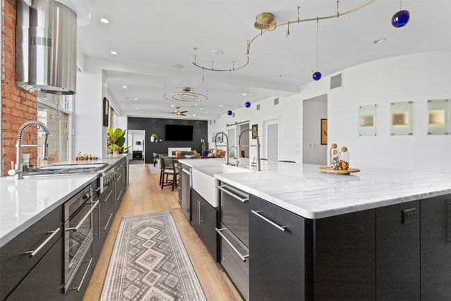 Kitchen featuring open floor plan, a spacious island, light wood-type flooring, dark cabinets, and visible vents | Image 7