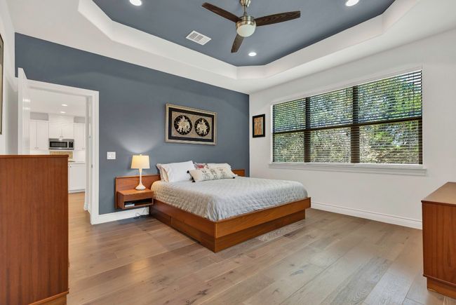 Bedroom with a raised ceiling, hardwood / wood-style flooring, recessed lighting, and ceiling fan | Image 11