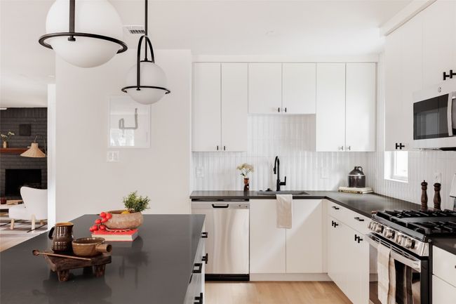 Kitchen featuring appliances with stainless steel finishes, dark countertops, backsplash, and white cabinetry | Image 13