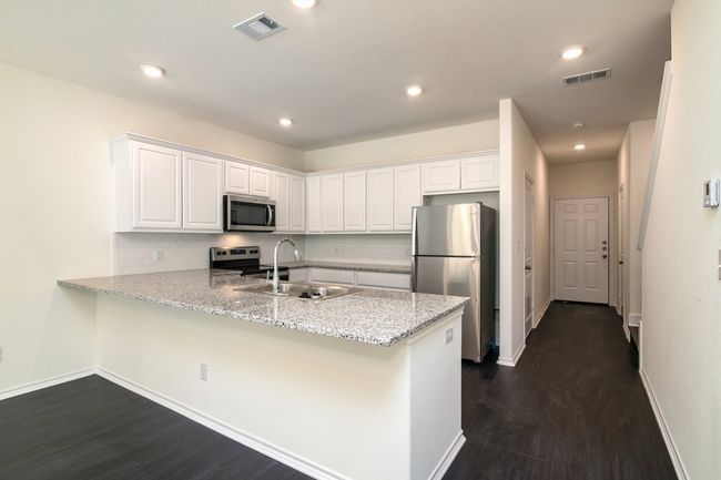 Kitchen with white cabinets, appliances with stainless steel finishes, kitchen peninsula, and sink | Image 6