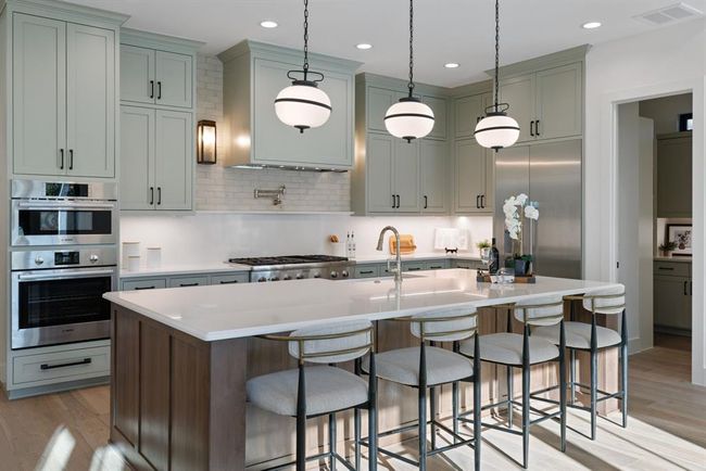 Kitchen with appliances with stainless steel finishes, a sink, light wood finished floors, backsplash, and recessed lighting | Image 17