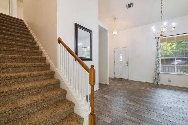 Entryway featuring visible vents, stairs, baseboards, a chandelier, and dark wood finished floors | Image 23
