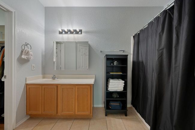 Full bathroom with vanity, tile patterned flooring, baseboards, and curtained shower | Image 17